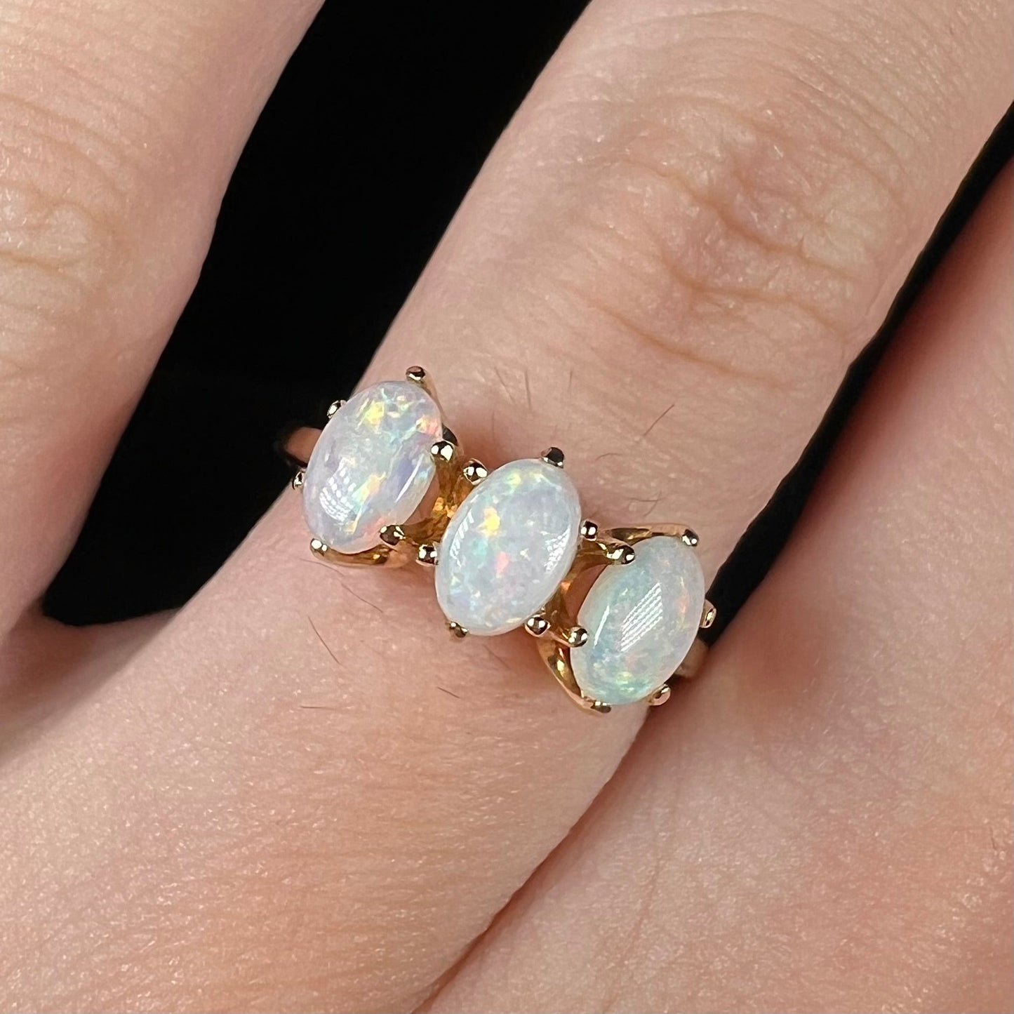 A vintage yellow gold ring mounted with three oval cut white Australian opals.