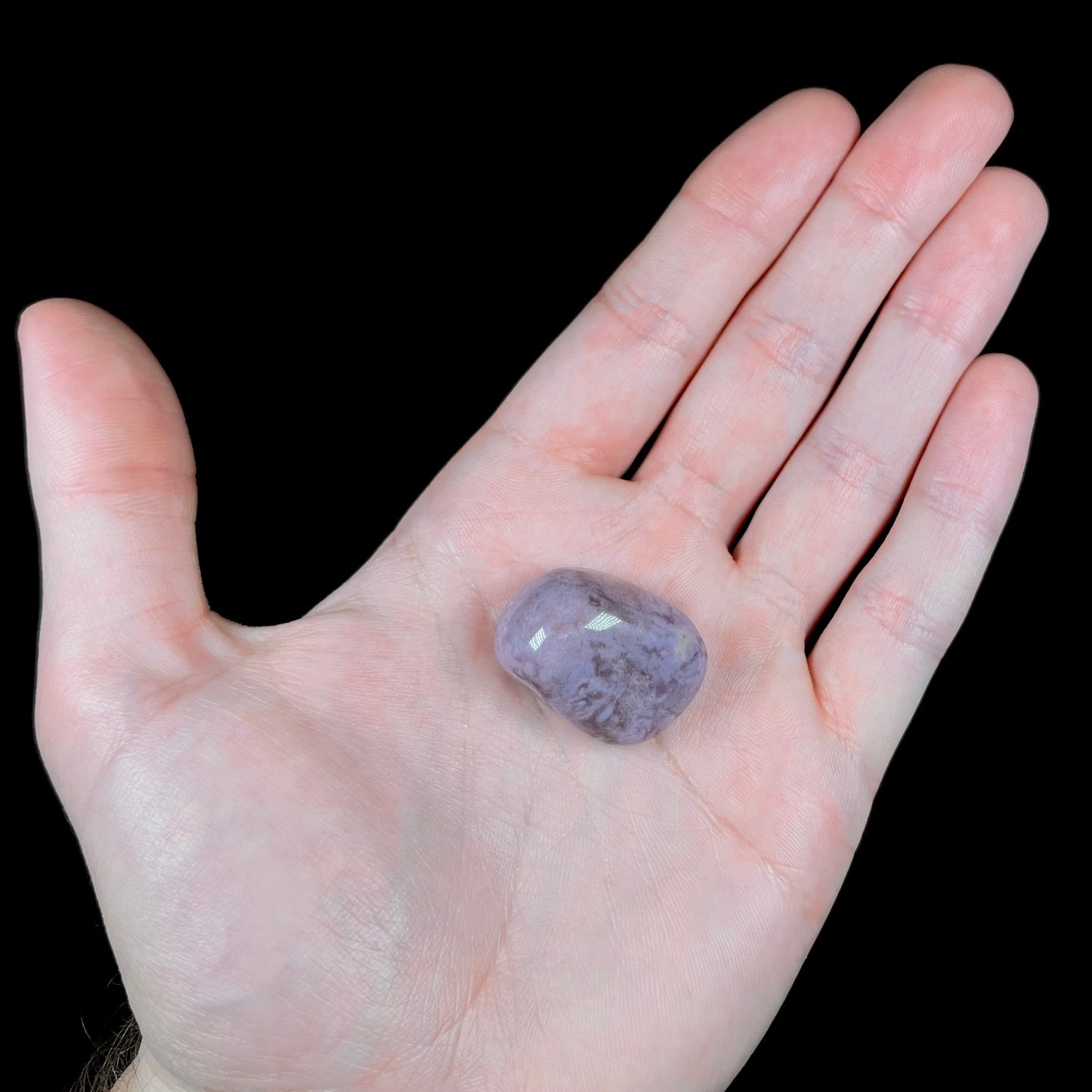 A tumbled Turkish purple jade stone. The material is a "white" lilac purple color.