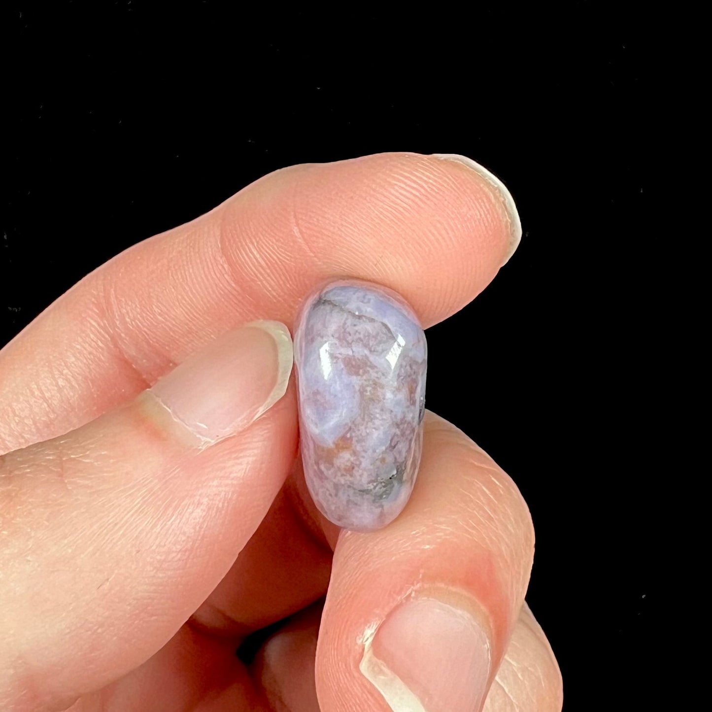 A tumble polished turkiyenite purple jade stone from Bursa, Turkey. Material has reddish marbling.