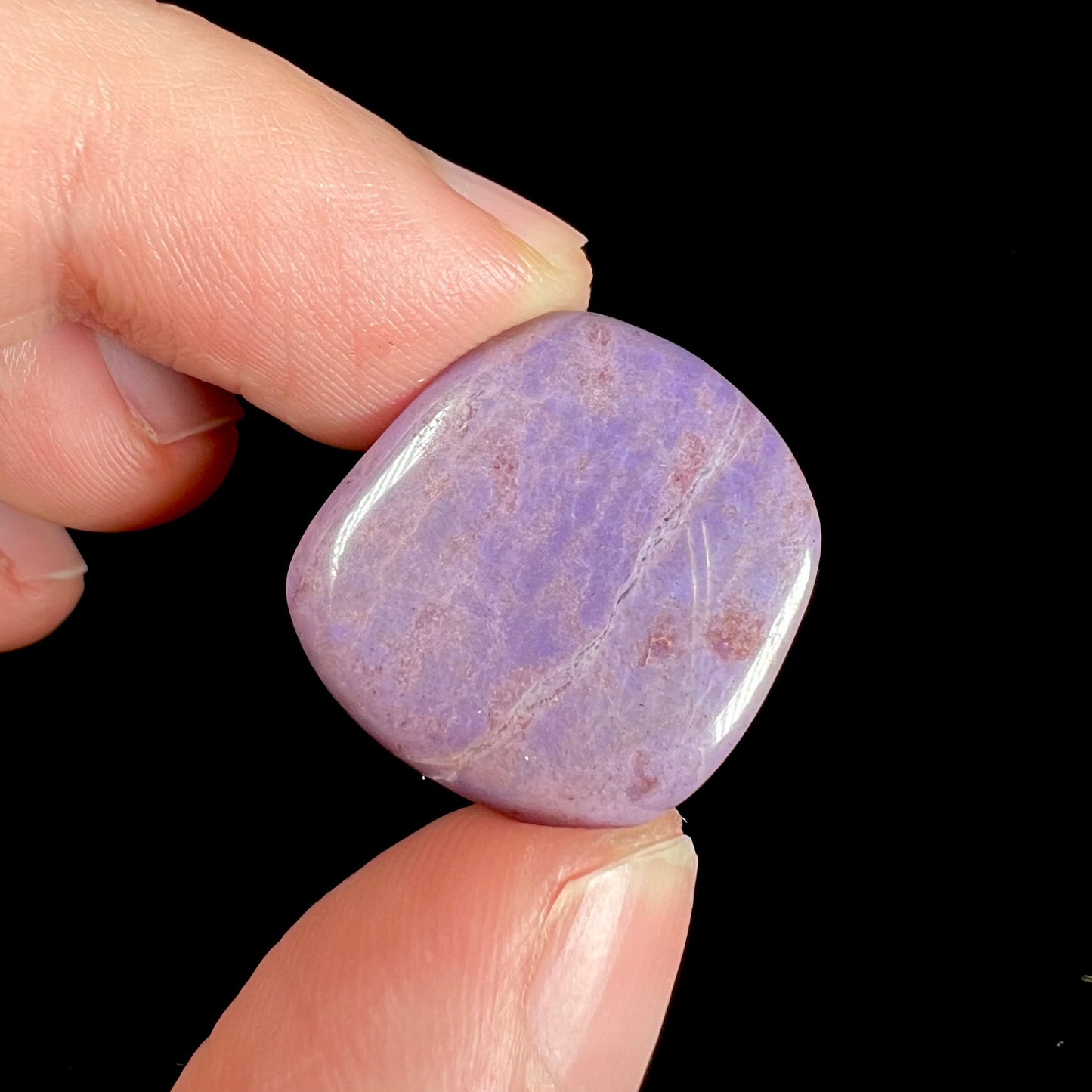 A tumbled turkiyenite jade stone from Bursa, Turkey. The rock is purple with red speckles.