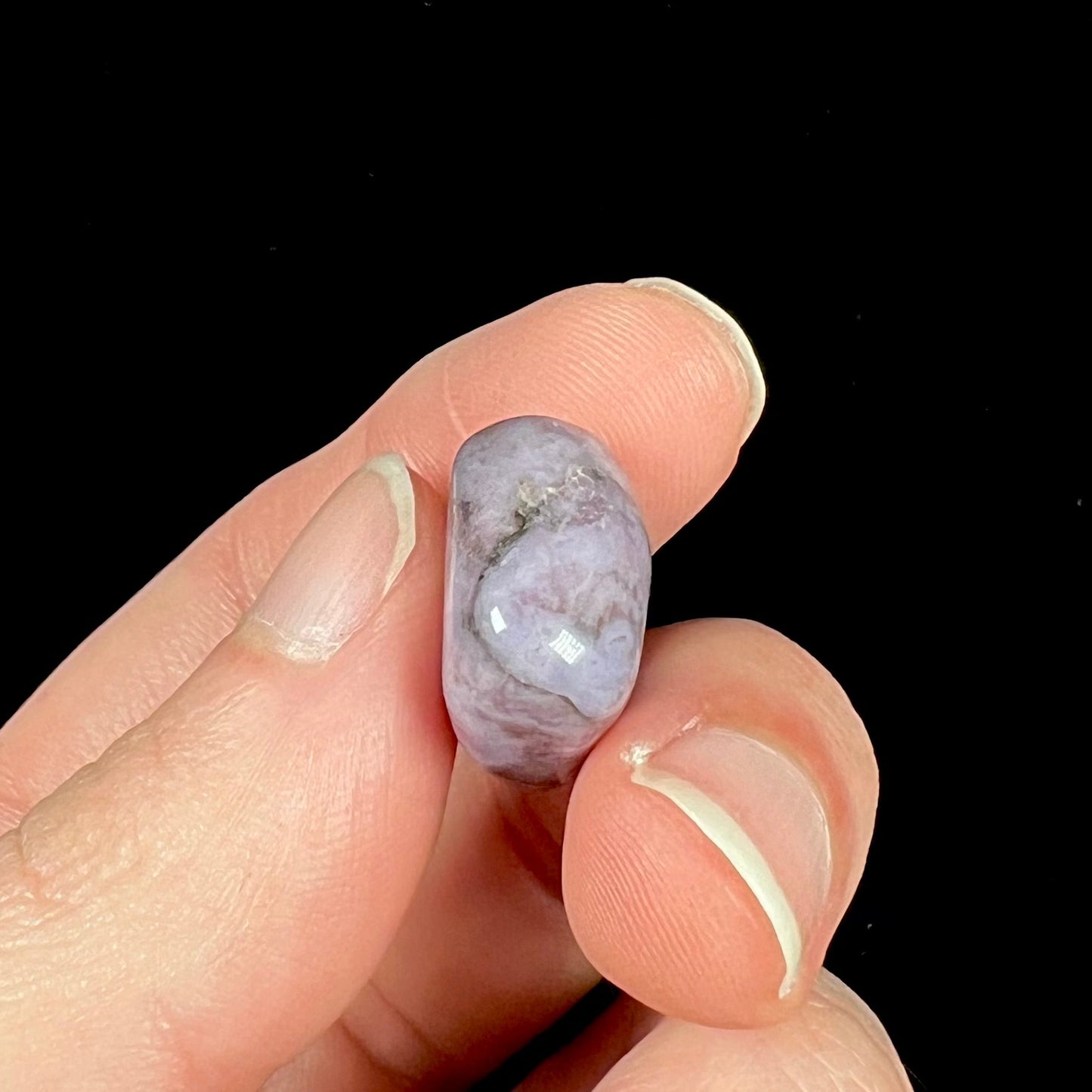 A tumble polished turkiyenite purple jade stone from Bursa, Turkey. Material has reddish marbling.