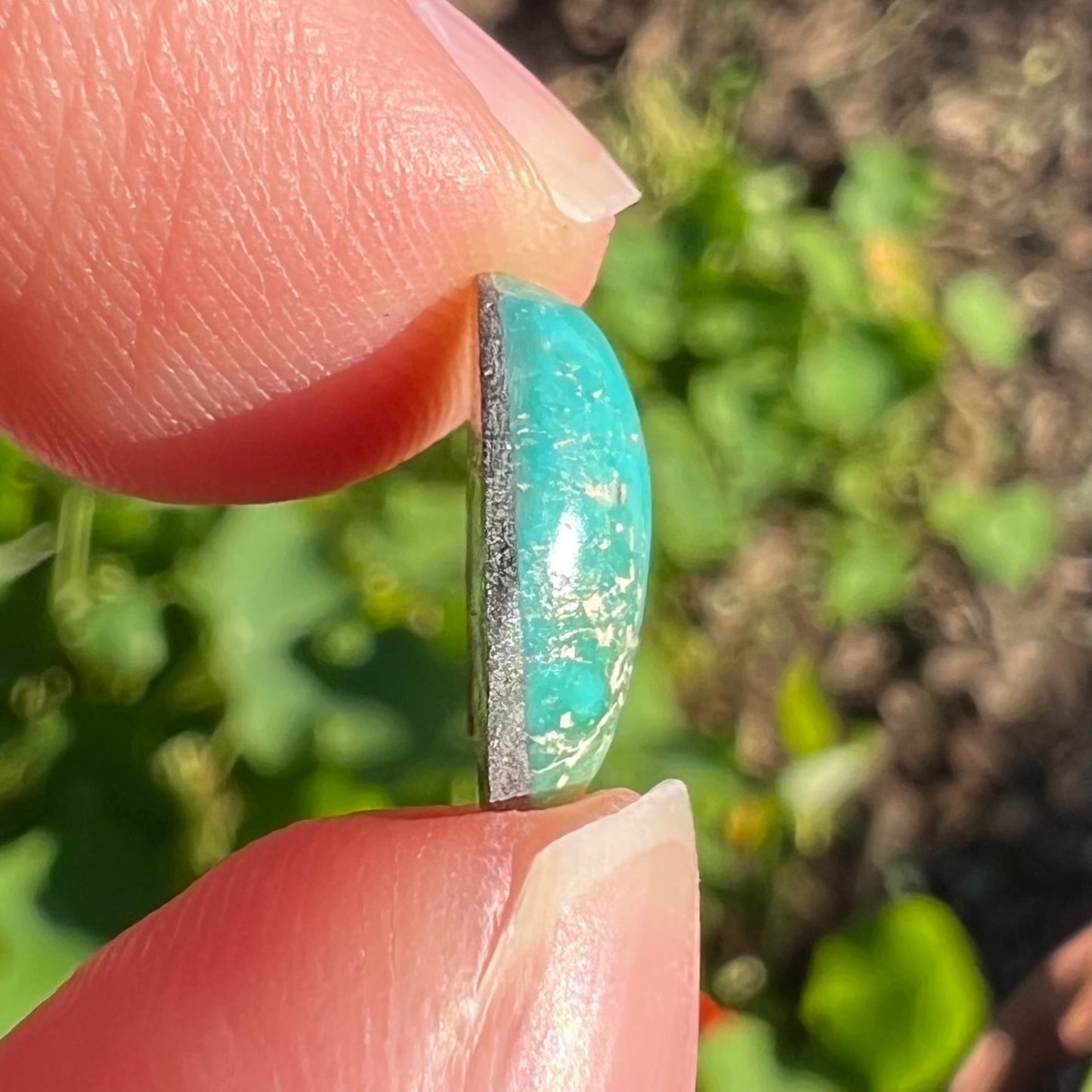 A loose, freeform cut Pilot Mountain turquoise cabochon. The stone is greenish blue.