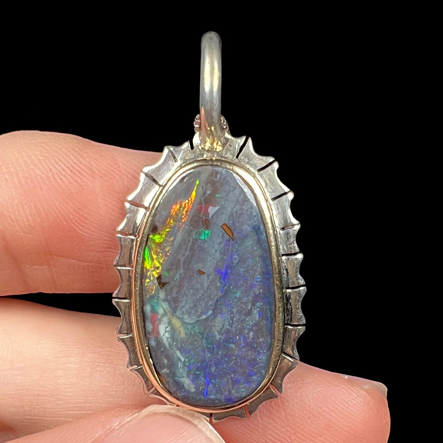 A Southwest style two-tone sterling silver pendant set with a black boulder opal with a yellow gold bezel.