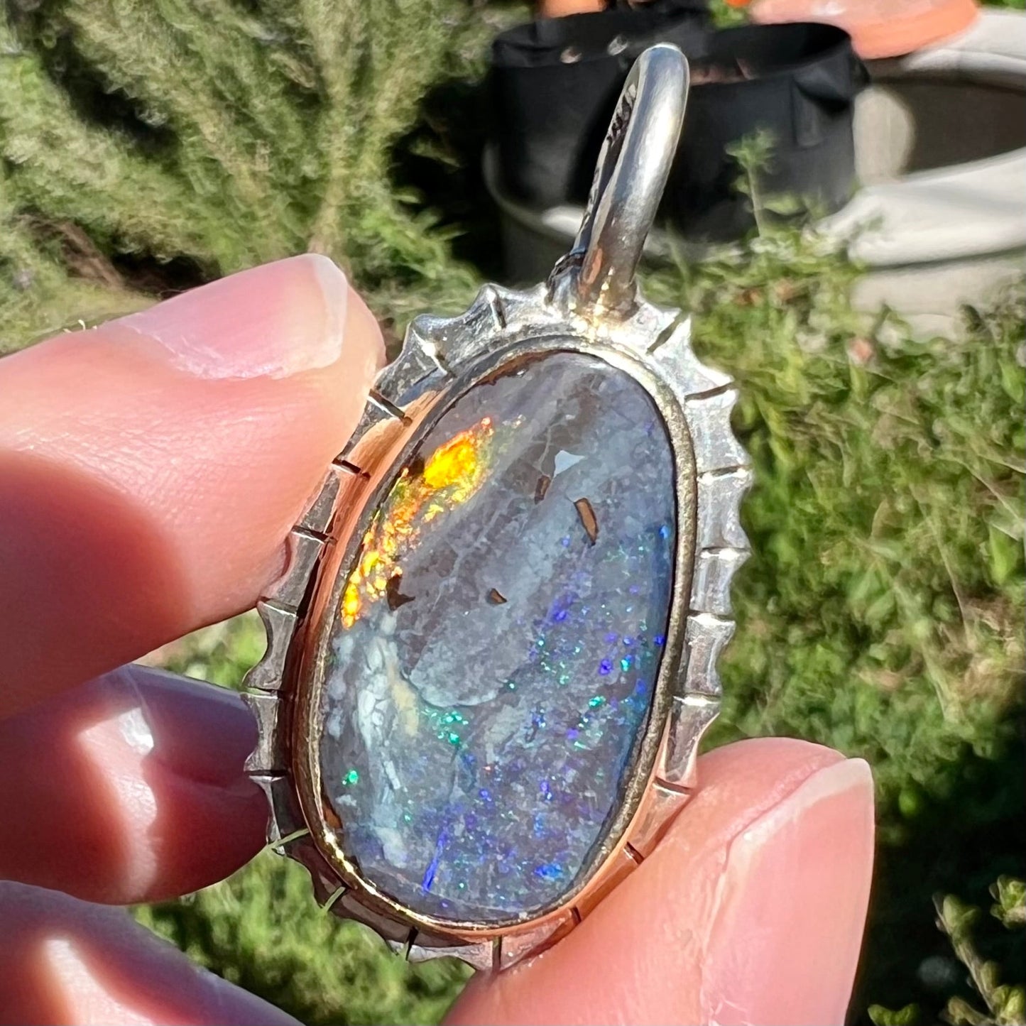 A Southwest style two-tone sterling silver pendant set with a black boulder opal with a yellow gold bezel.