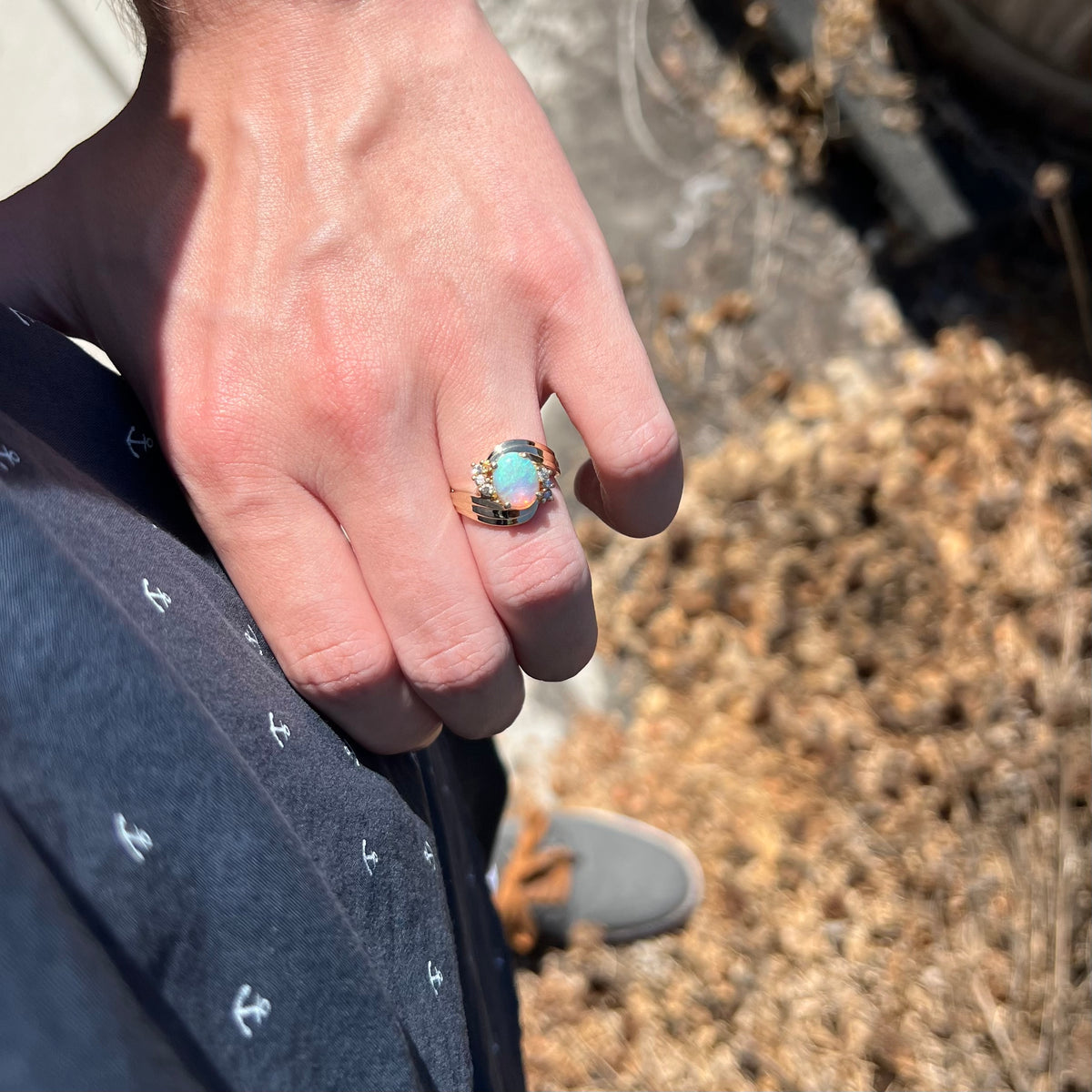 Person's sunlit hand resting on hip wearing vintage 1980s era 14k gold opal and diamond bypass ring