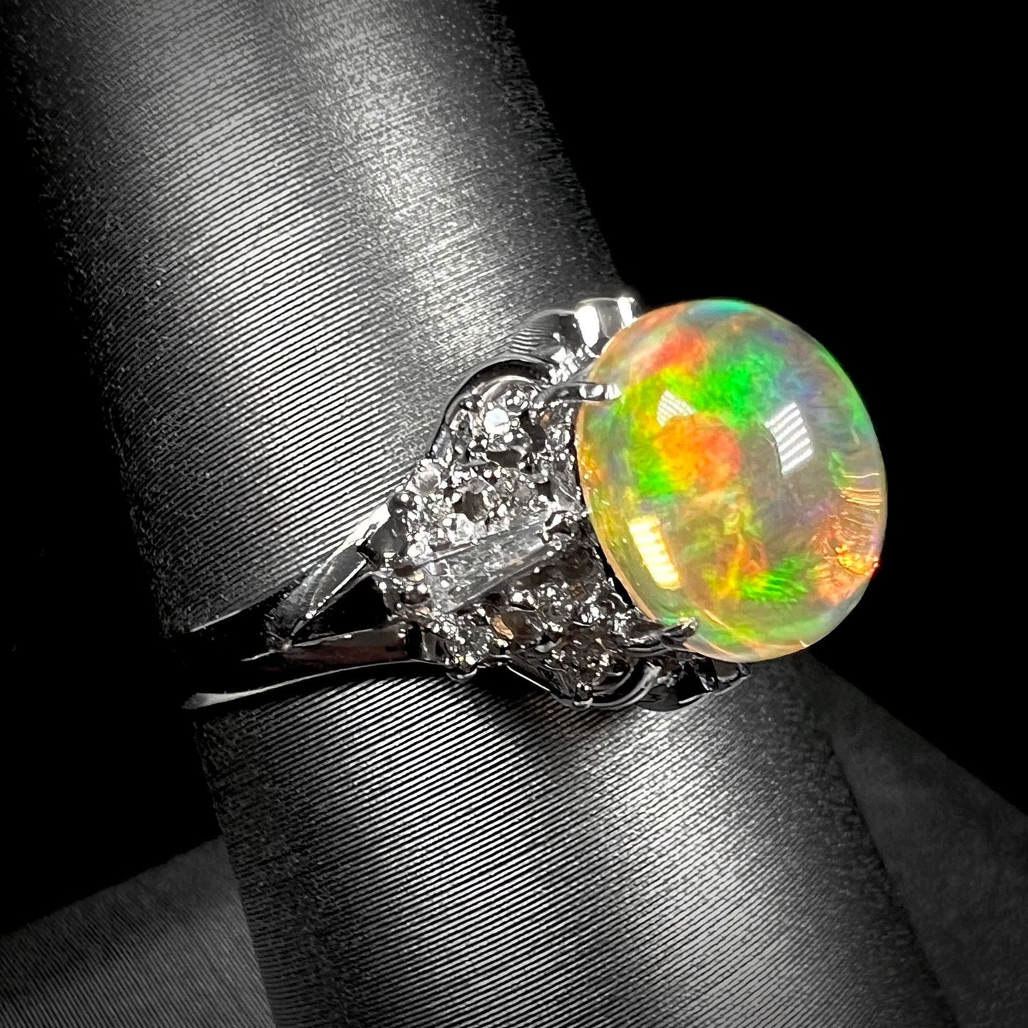 A platinum filigree ring mounted with a high-domed Mexican fire opal and baguette cut diamond accents.