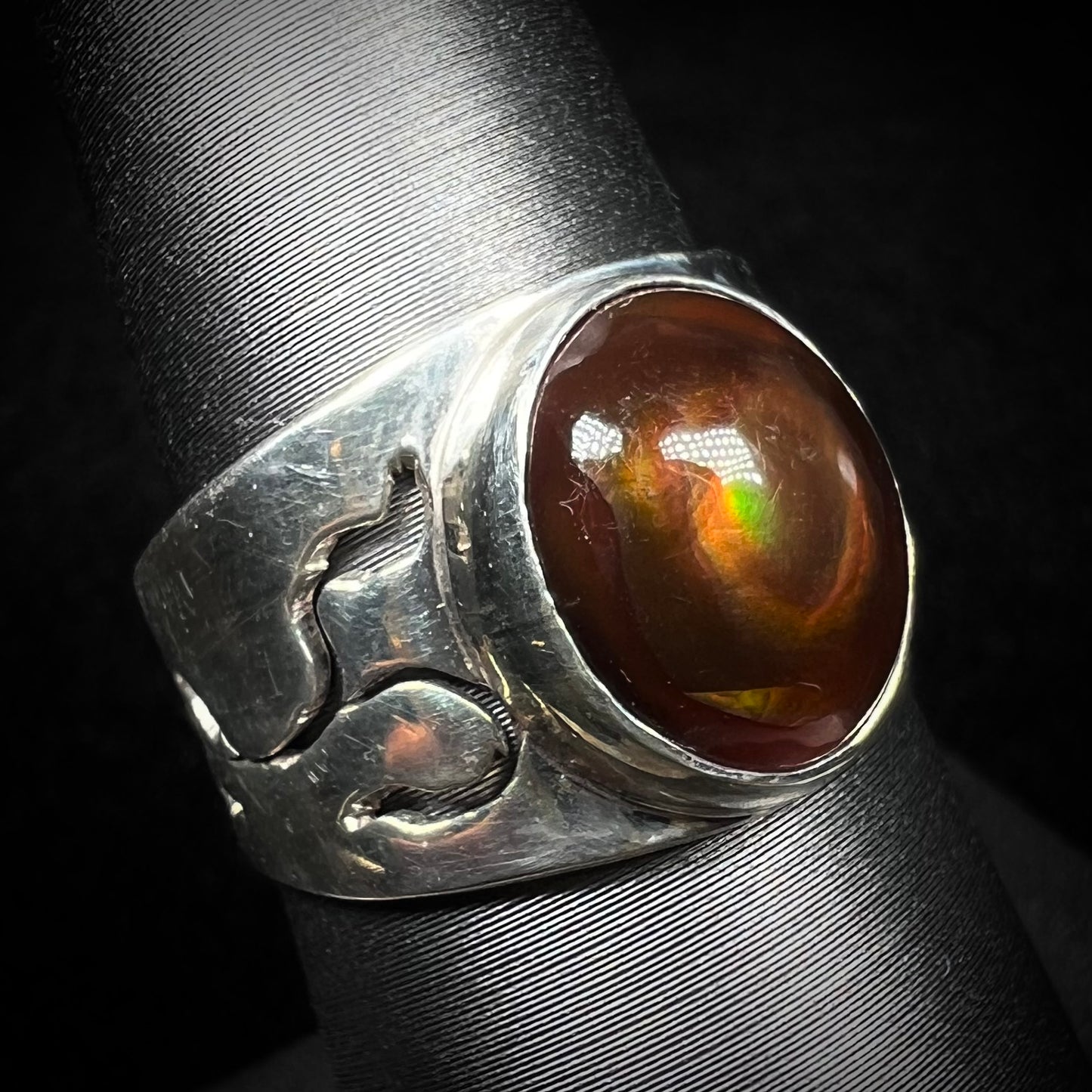 A vintage Mexican fire agate ring in sterling silver, shown from an angle against a dark backdrop.