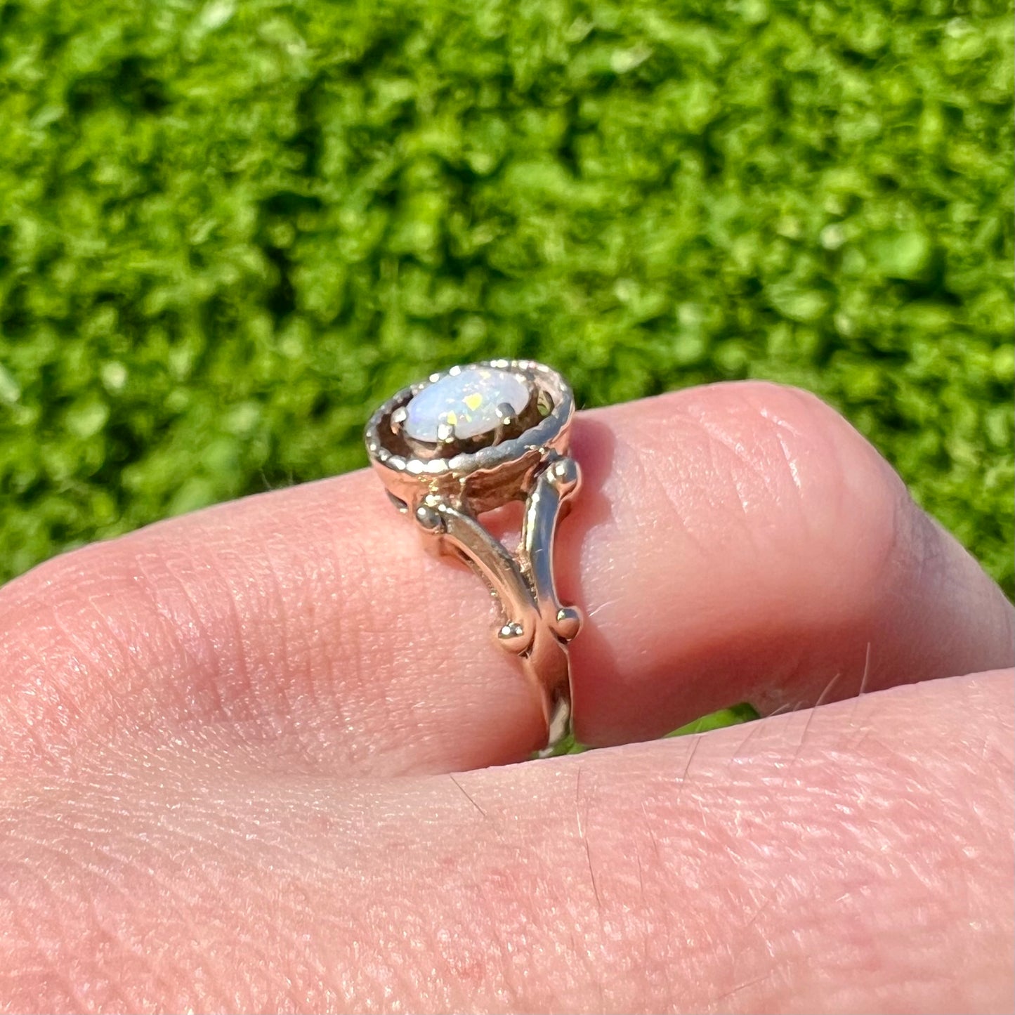 A ladies' Art Nouveau style opal solitaire ring. The mounting is yellow gold with filigree accents.