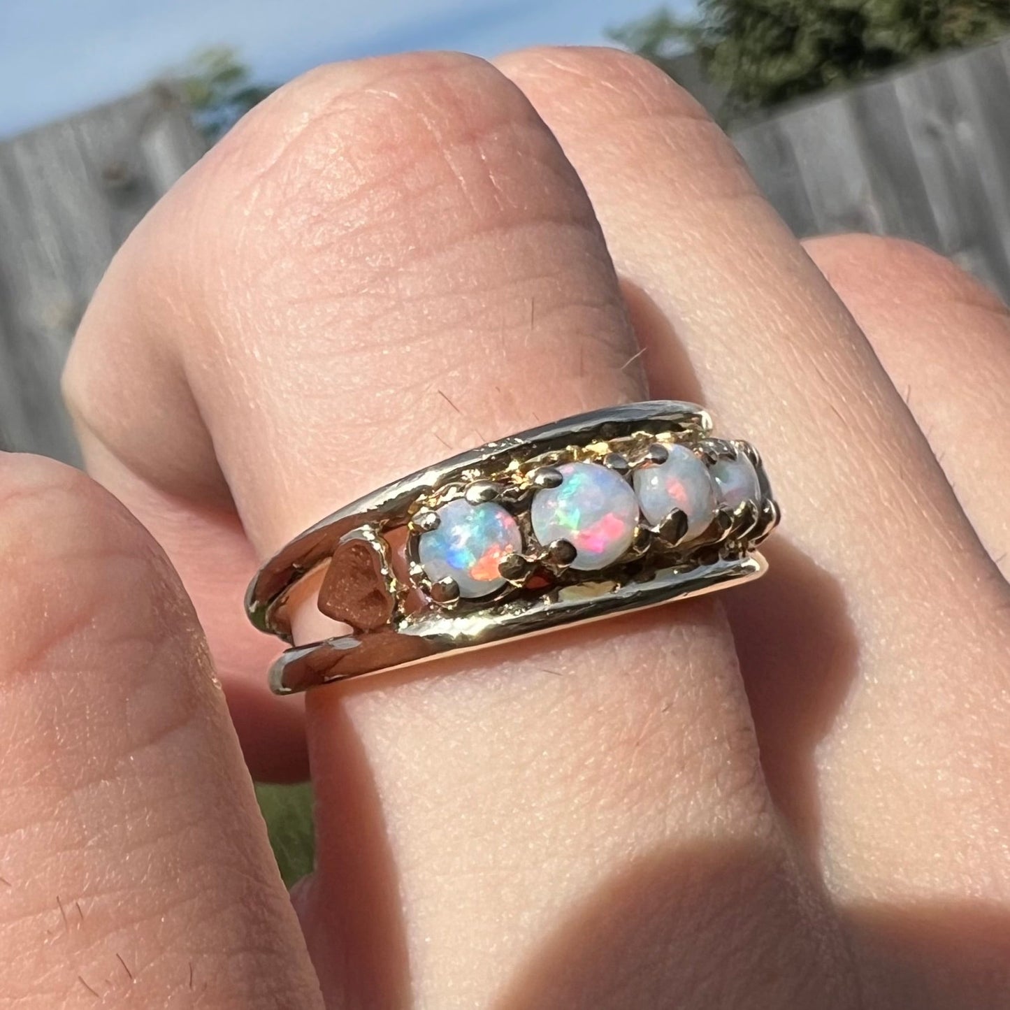 A yellow gold band set with five round cabochon cut opals and heart design accents.
