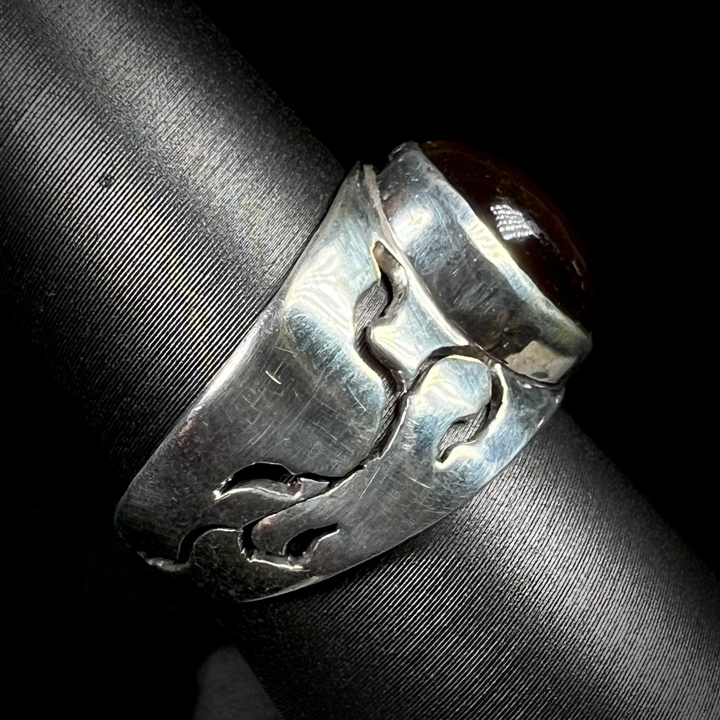 A vintage sterling silver fire agate ring shown from the side profile, displaying its open, vine-like design.
