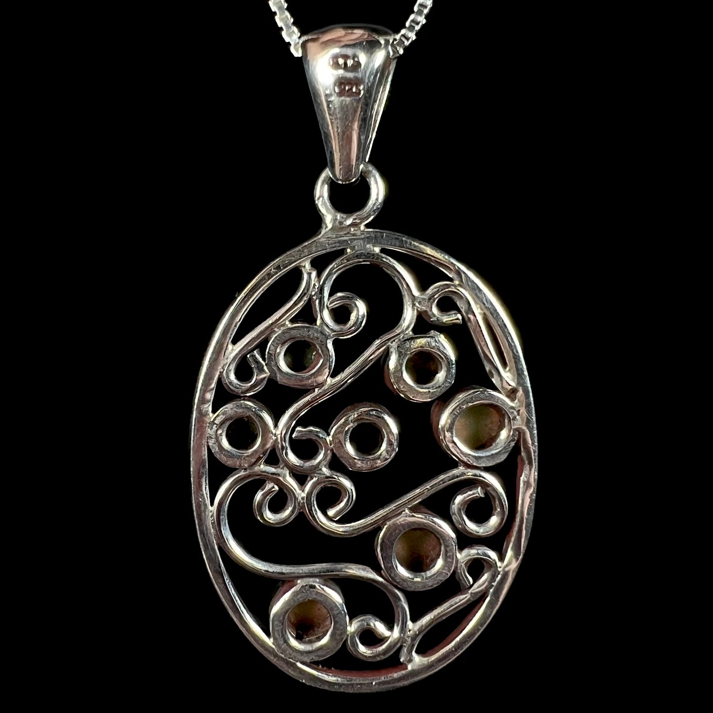 Back side of a vintage-style sterling silver filigree pendant, shown against a black background.