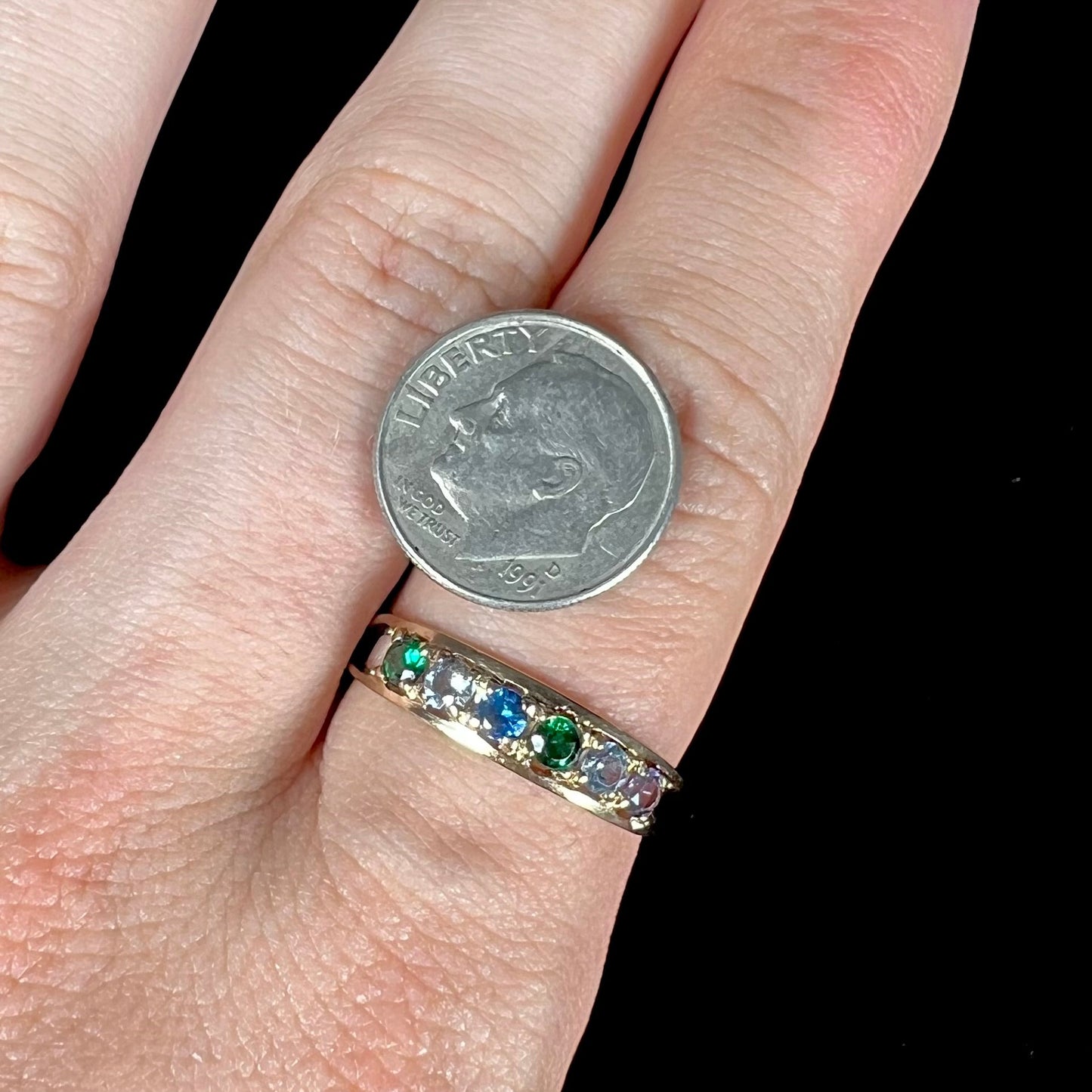 A ladies' yellow gold band set with green, dark blue, light blue, and light purple stones.