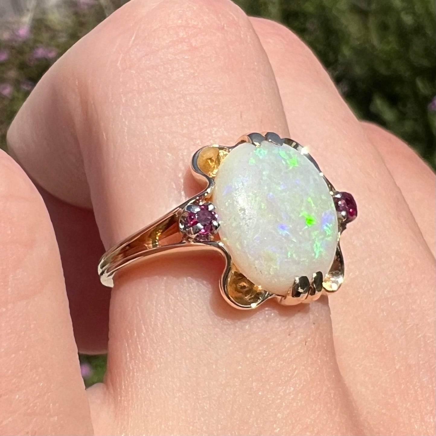 A turn of the century Art Nouveau opal and pink sapphire ring. The ring is yellow gold and palladium. The opal is green and purple.