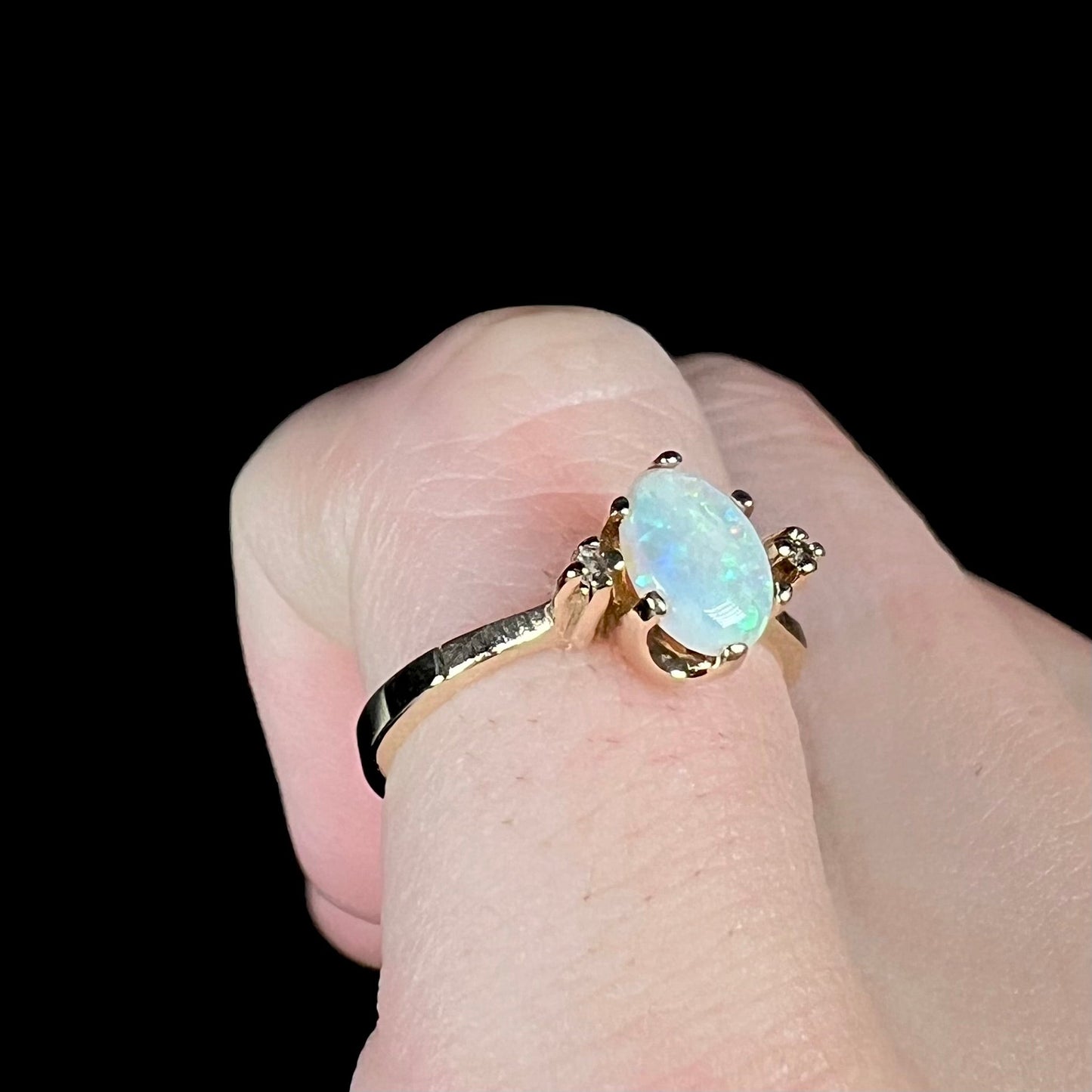 A dainty, 1960's style opal and diamond engagement ring. The ring is prong-set and yellow gold.