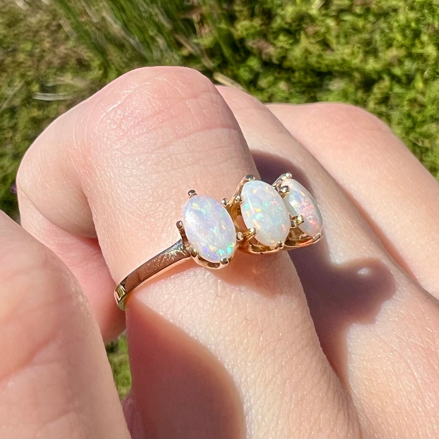 A vintage yellow gold ring mounted with three oval cut white Australian opals.