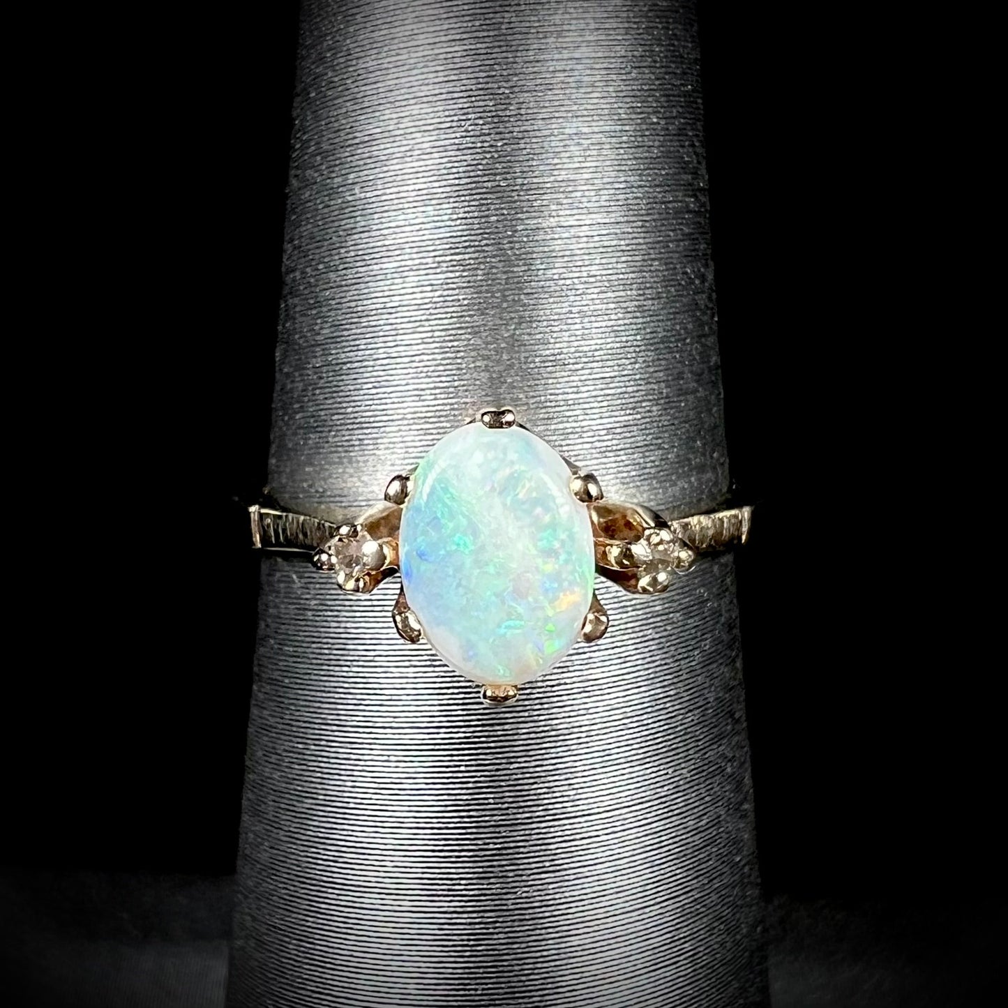 A dainty, 1960's style opal and diamond engagement ring. The ring is prong-set and yellow gold.