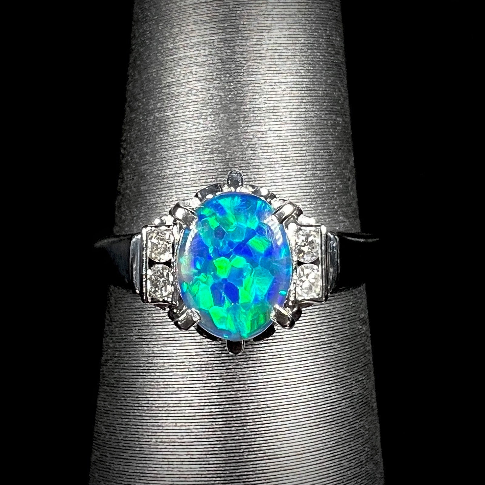 A vivid Lightning Ridge black opal engagement ring in platinum, featuring intense green fire and diamond accents in a delicate Japanese-crafted setting.