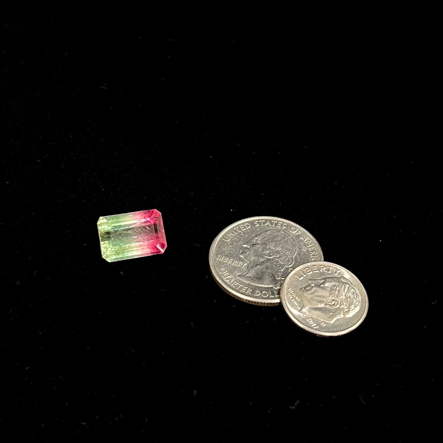 A loose watermelon tourmaline gemstone. The stone is emerald cut and fades from hot pink to green.