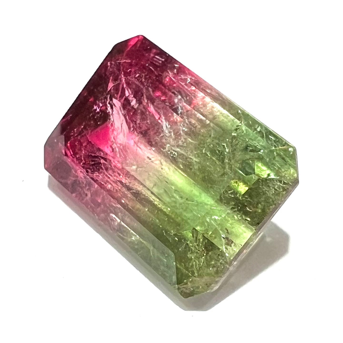 A loose watermelon tourmaline gemstone. The stone is emerald cut and fades from hot pink to green.