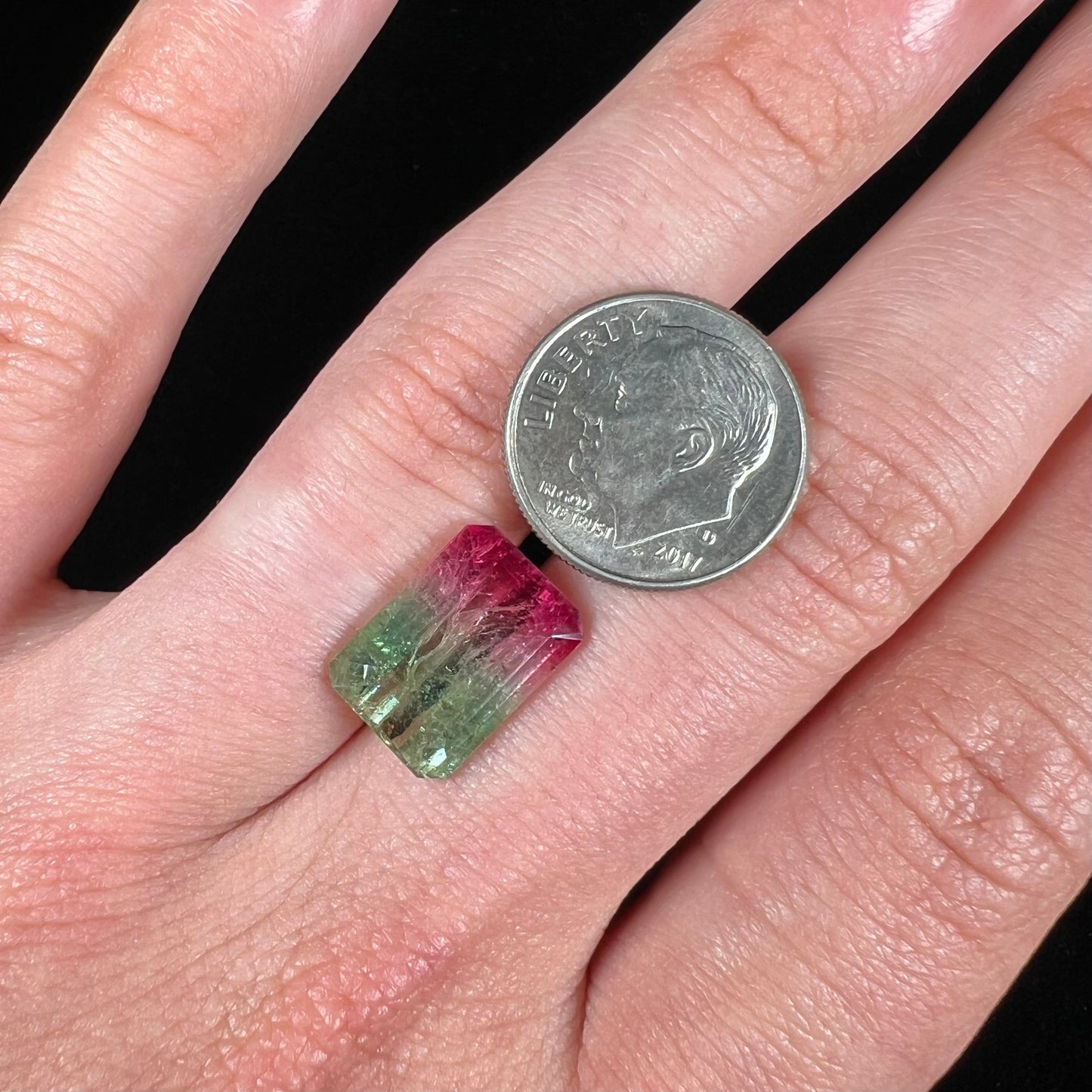 A loose watermelon tourmaline gemstone. The stone is emerald cut and fades from hot pink to green.