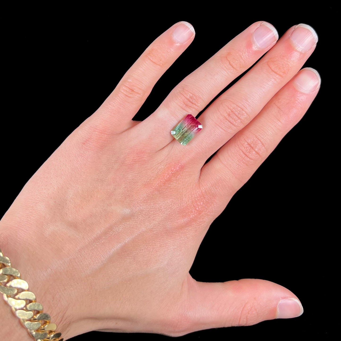 A loose watermelon tourmaline gemstone. The stone is emerald cut and fades from hot pink to green.