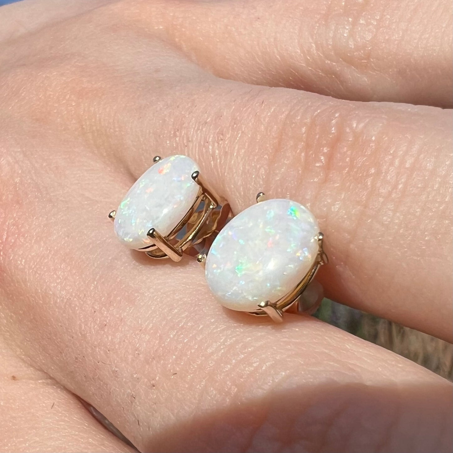 Opposing angle of opal studs in sunlight showing faint red and green color play.