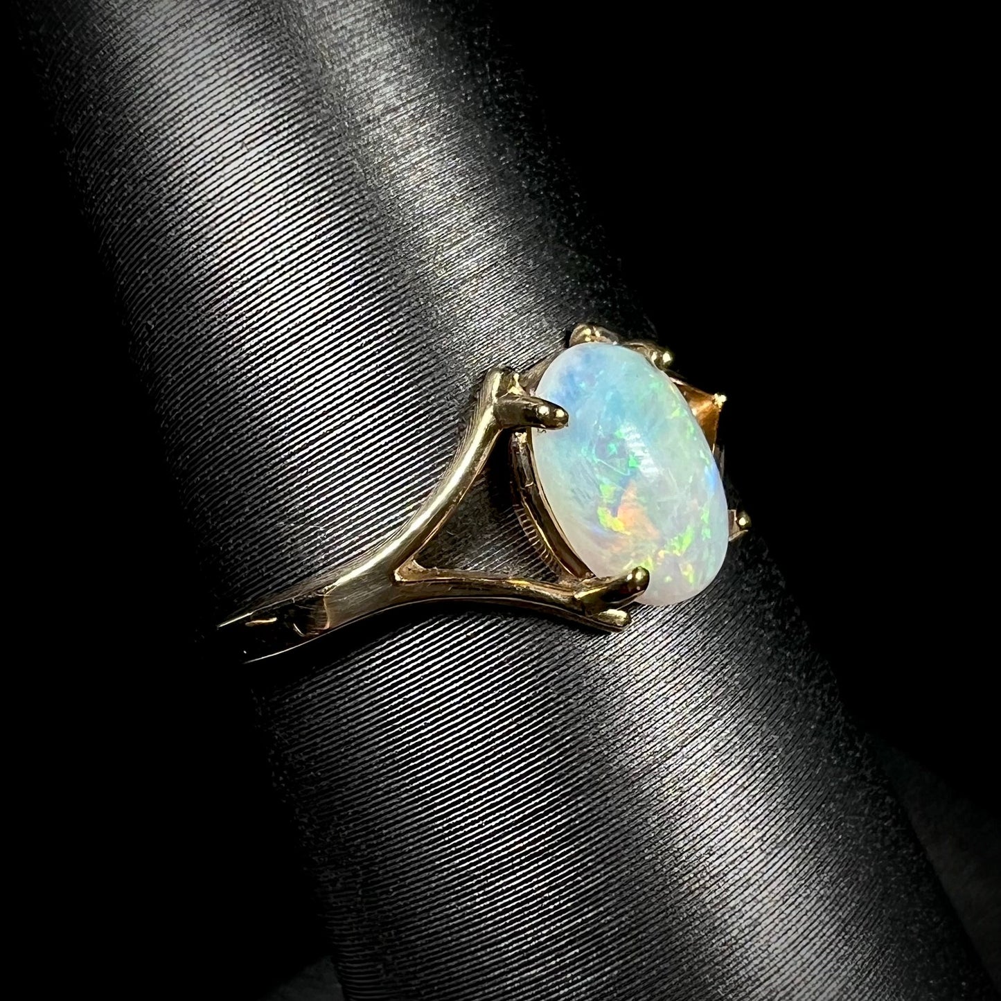 A ladies' simple opal solitaire ring. The ring is yellow gold with a split shank.