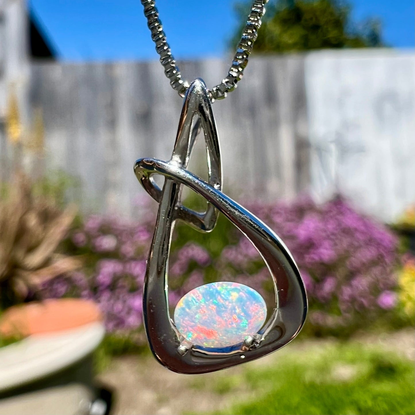 A ladies' sterling silver pendant set with an oval cabochon cut natural white crystal opal.