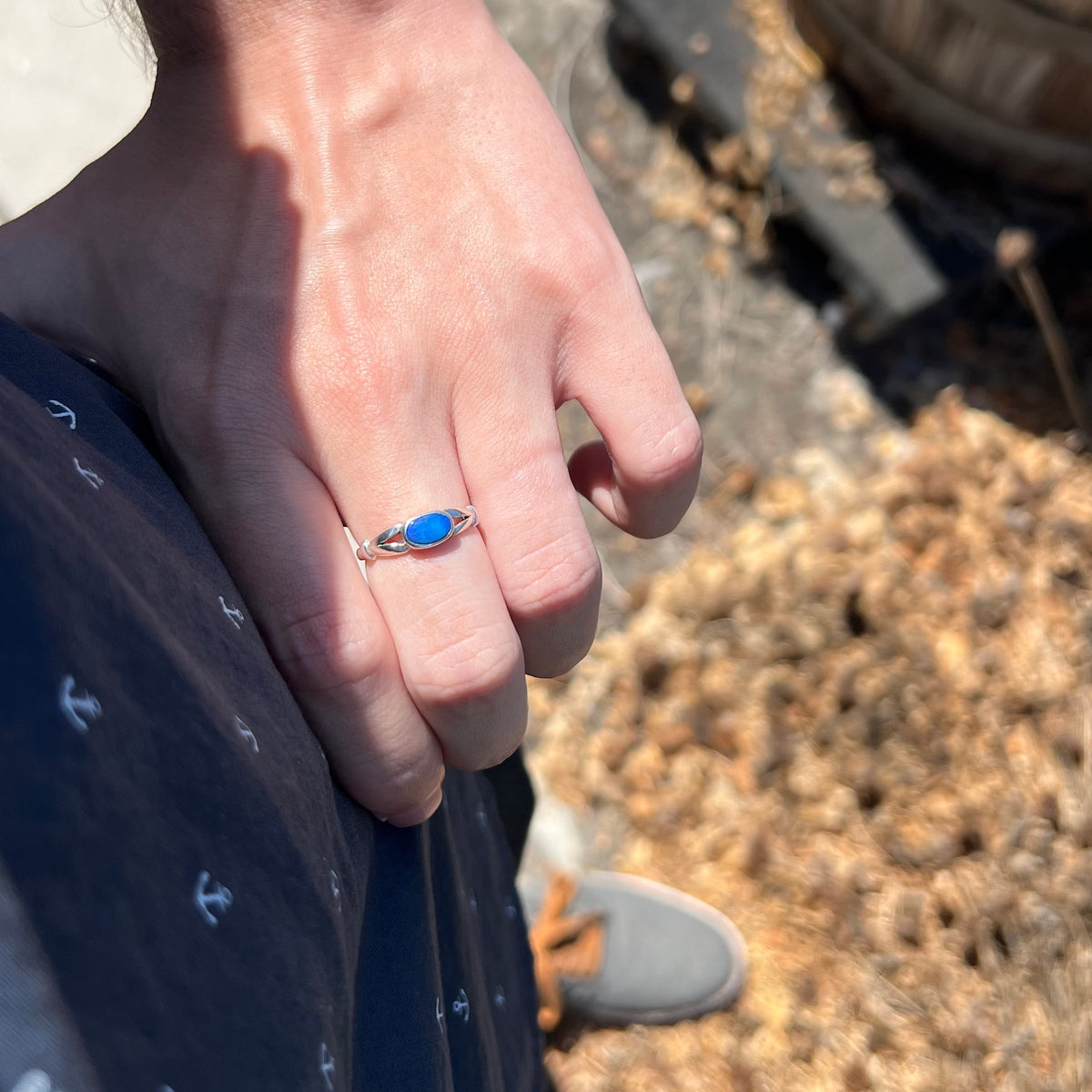 Person's hand resting on hip in sunlight wearing women's blue Australian opal doublet ring