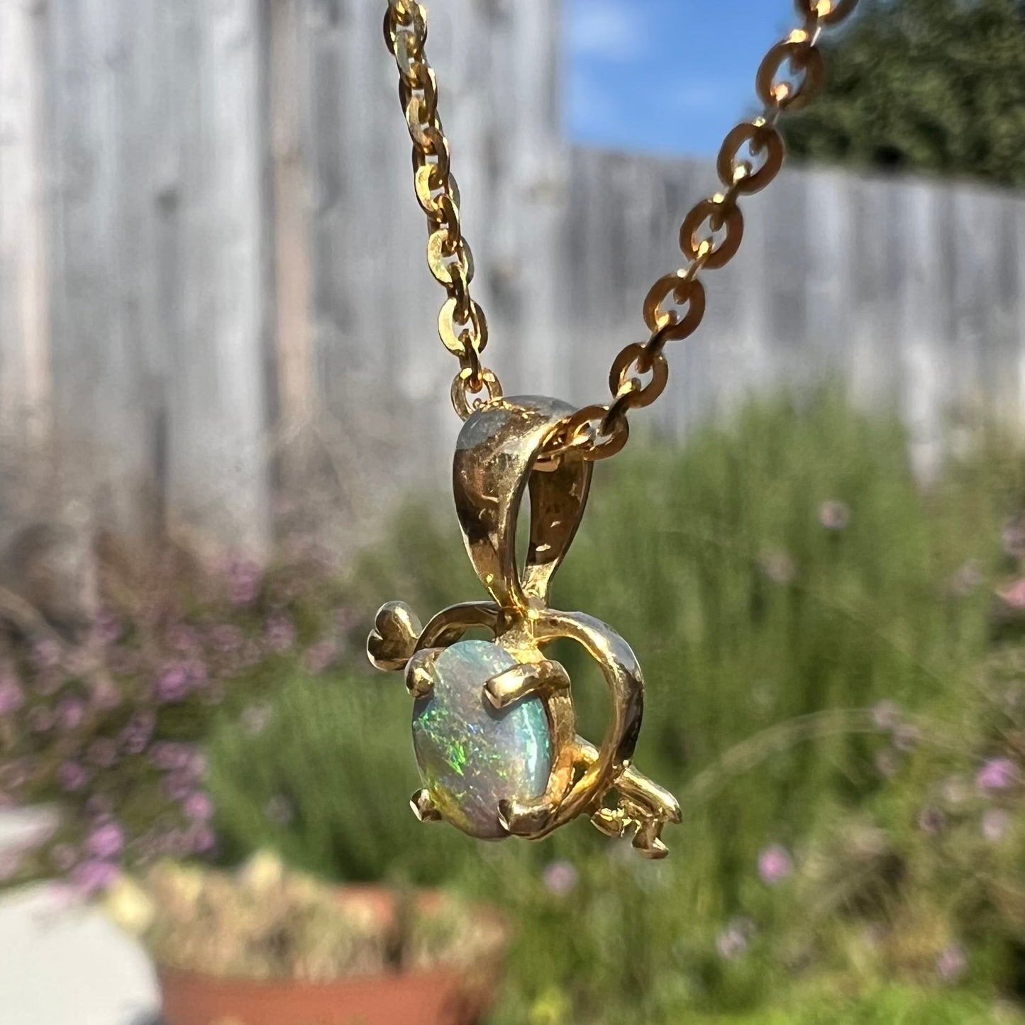 An 18 karat yellow gold heart and key design pendant set with an oval cut Australian black opal.