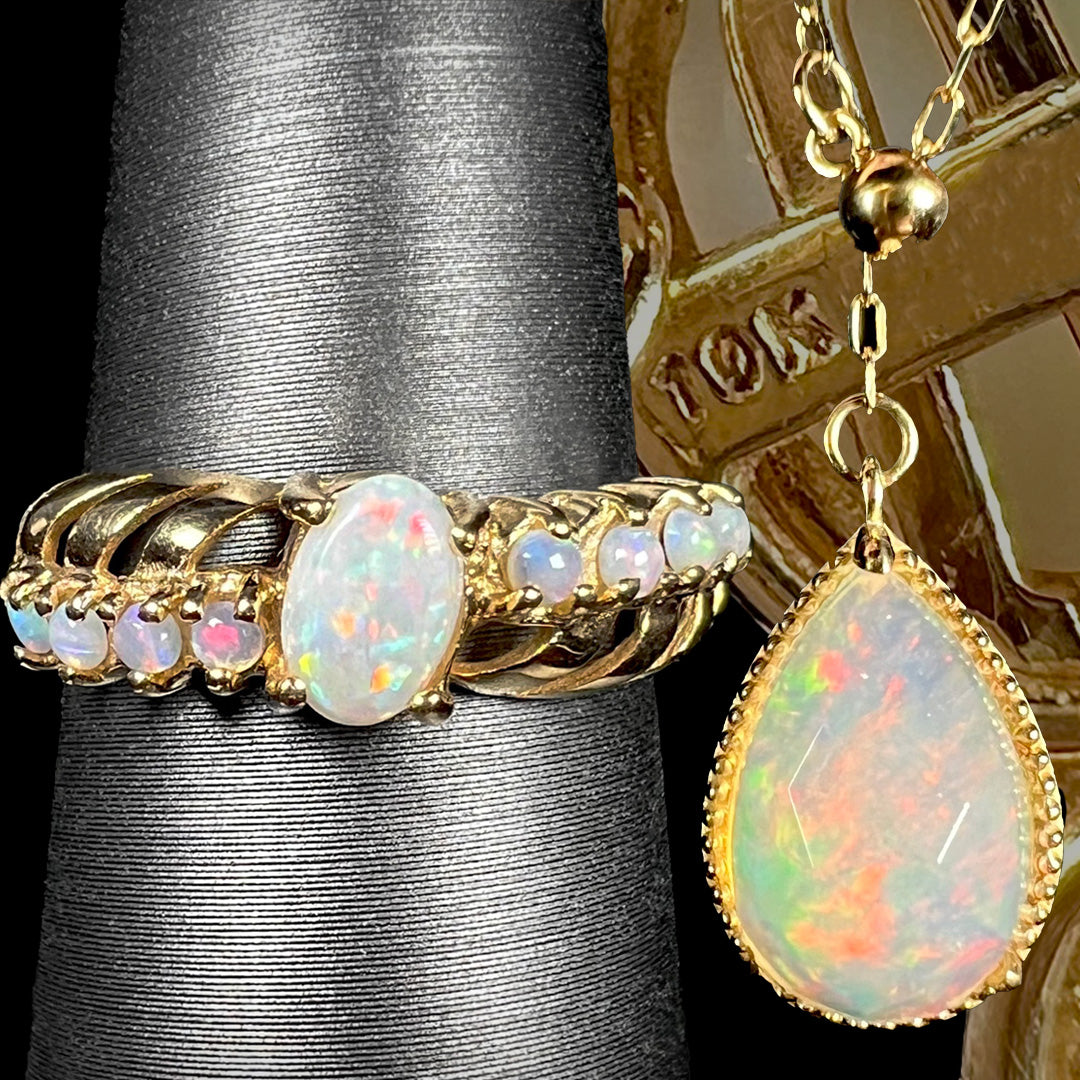 10k gold multi-stone opal ring on ring display next to pear-shaped 10k gold opal necklace in front of bracelet with "10K" hallmark stamp in focus.