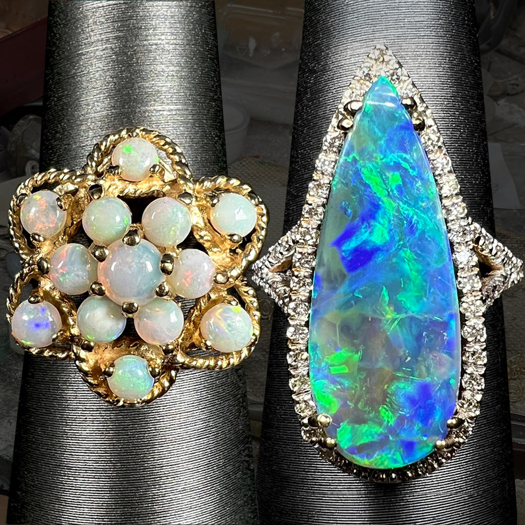 Two American-made opal rings shown on ring displays next to each other.  On the left, a gold atomic-style cluster ring; on the right, a pear-shaped boulder opal and diamond halo ring.