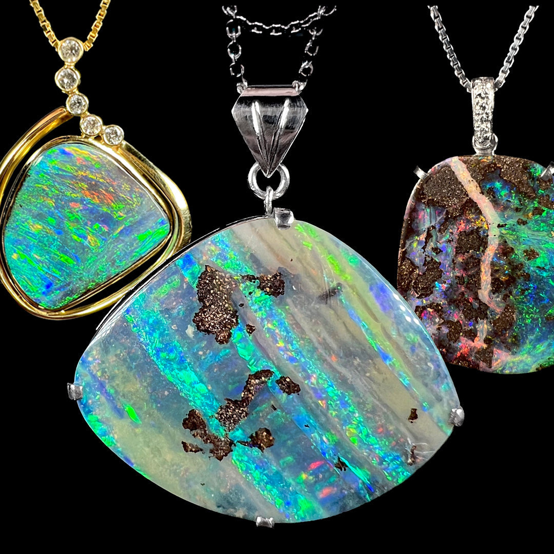 Three boulder opal pendants showing brilliant color play and ironstone matrix.  Two are platinum, and one is yellow gold.