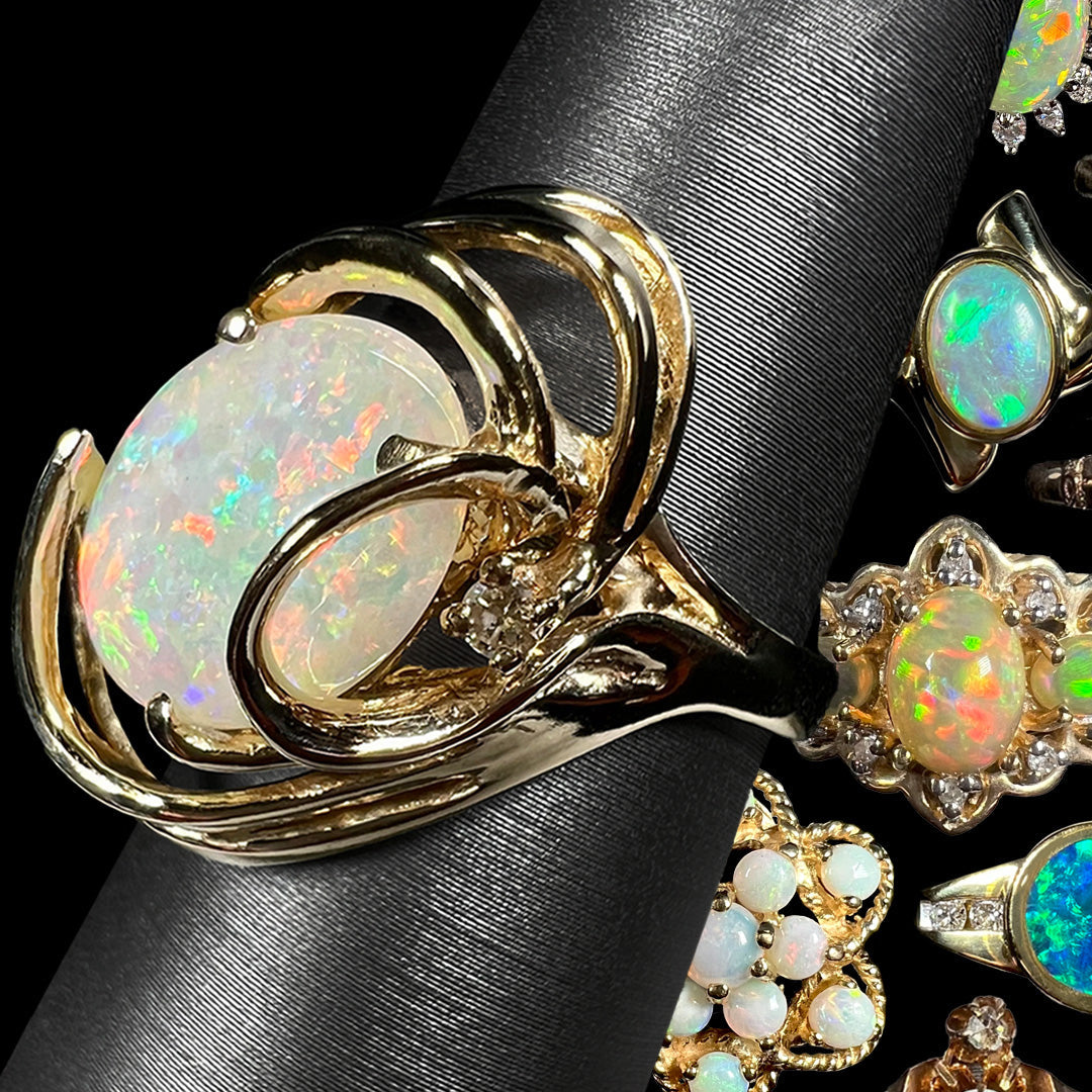 A Modernist style 14k gold Australian opal cocktail ring shown on a ring display from an angle in front of background of colorful yellow gold opal rings.