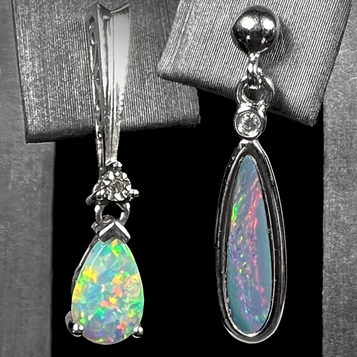 Two sterling silver opal dangle earrings shown on overlapping earring displays next to each other against a black background.