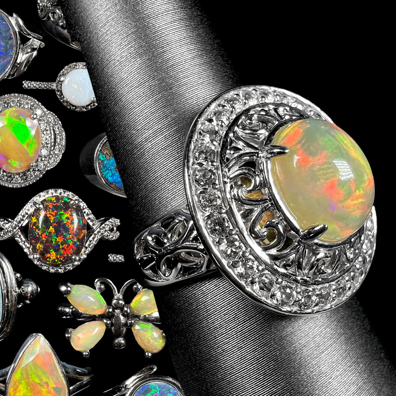 A sterling silver Ethiopian opal halo ring shown from an angle on a ring display in front of a collage of colorful sterling silver opal rings against a black background.