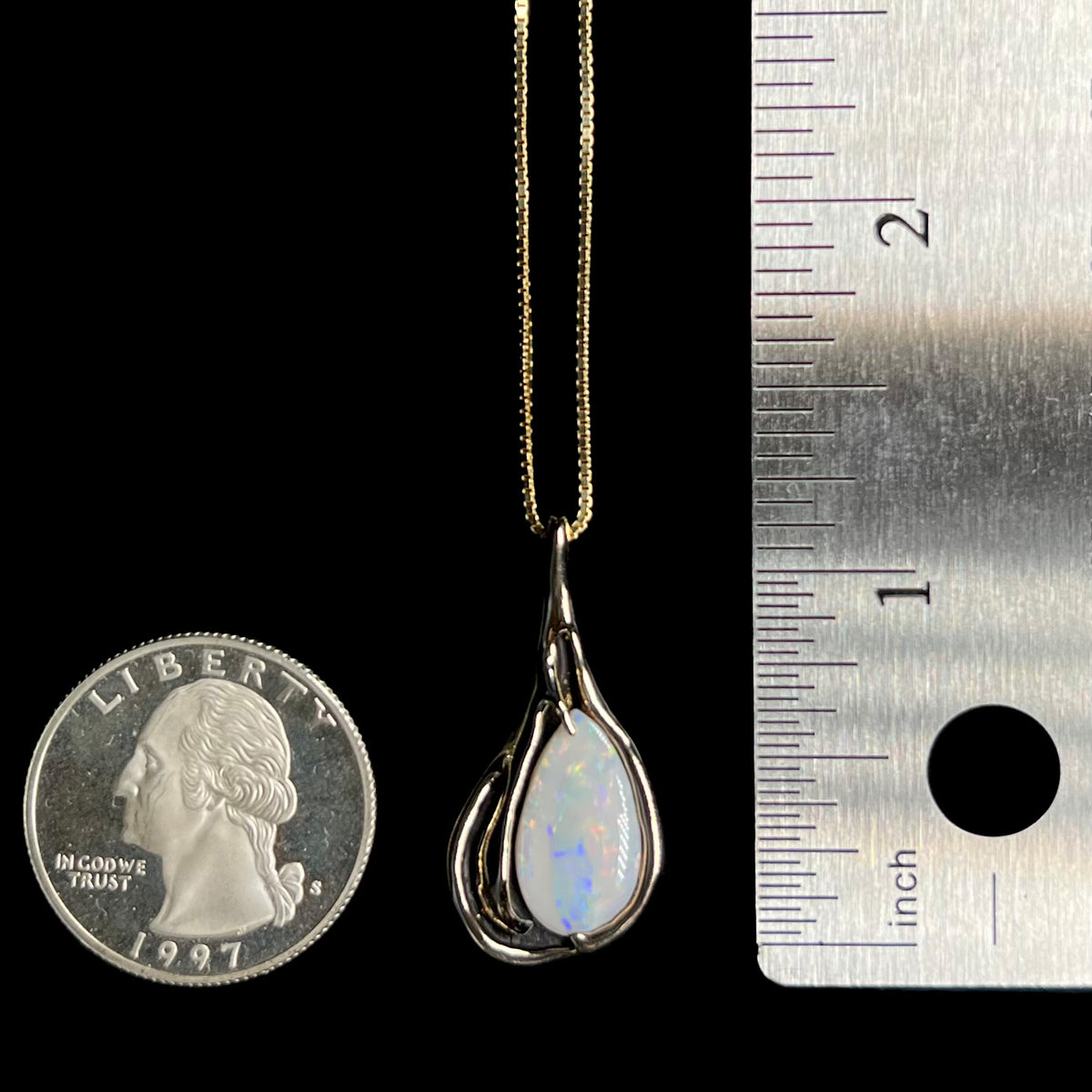 1.25 inch-long gold Australian opal pendant with Modernist design shown between US quarter coin and ruler