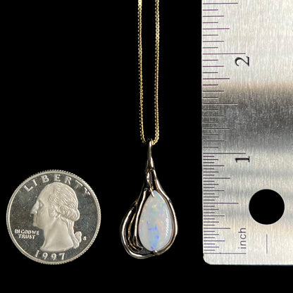 1.25 inch-long gold Australian opal pendant with Modernist design shown between US quarter coin and ruler