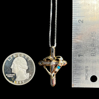 A 1.25 inch long sterling silver mother's diamond and opal cross pendant shown next to a quarter and ruler.