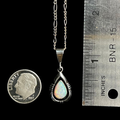 A sterling silver Navajo opal pendant measuring 1.25 inches long, next to a ruler and dime coin.