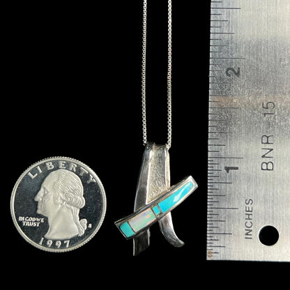 A folded design sterling silver turquoise and lab-created opal inlay necklace shown next to a quarter and ruler.