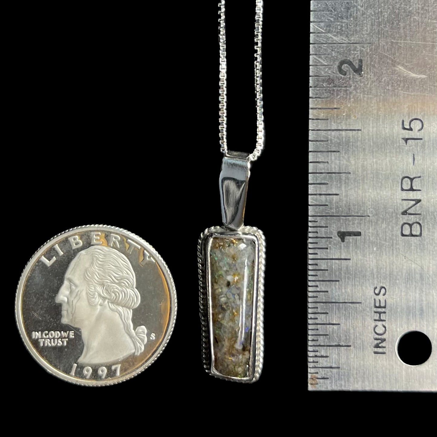 A 1.33 inch-long Louisiana matrix opal pendant in sterling silver, shown next to a quarter coin and ruler for scale.