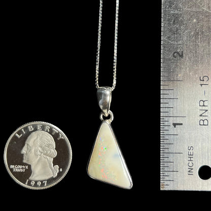 A 1.5 inch long Australian white boulder opal pendant in .950 silver, shown next to a ruler and quarter coin.