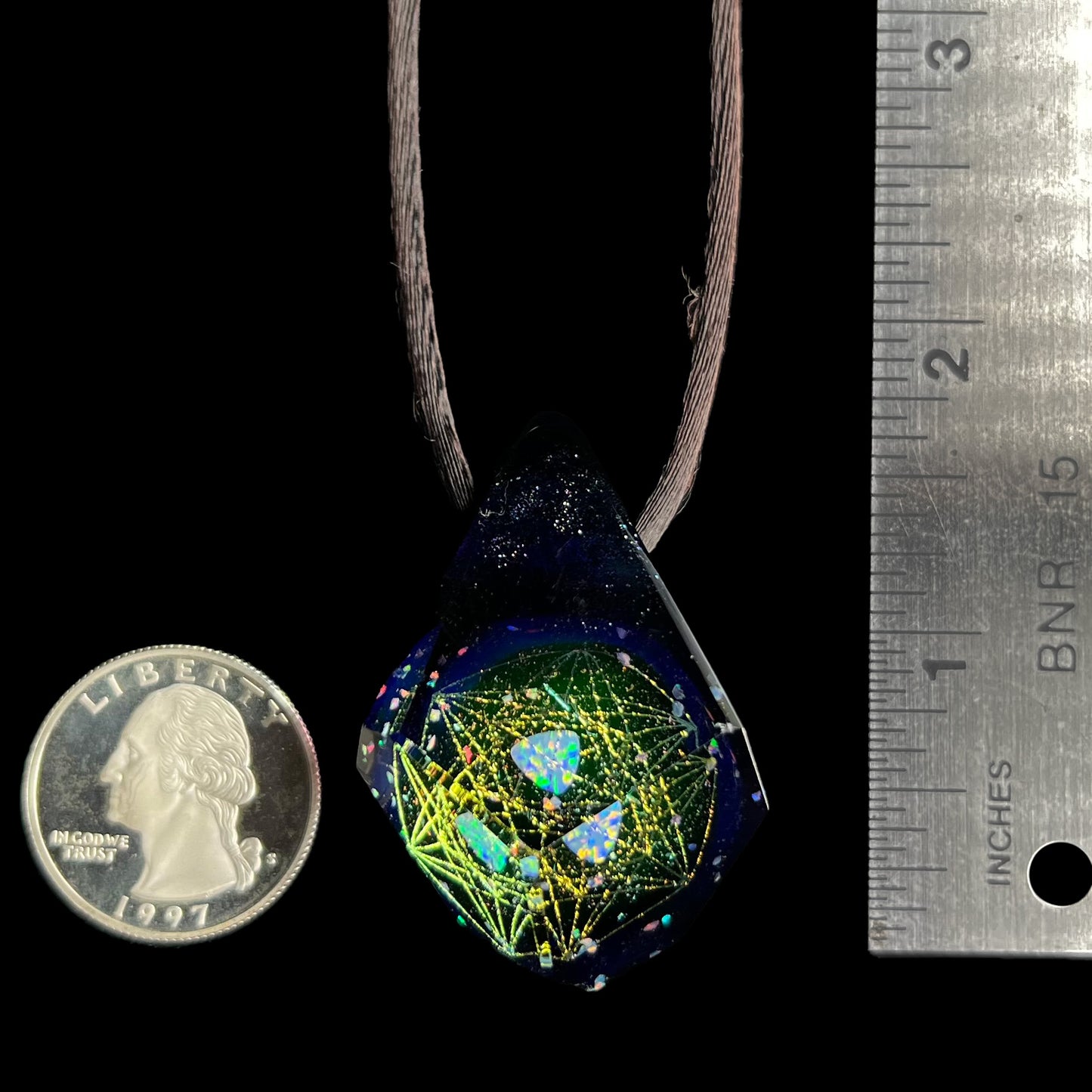A 1.7 inch-long faceted glass pendant with a trillion cut opal inside, shown next to a ruler and quarter coin for scale.