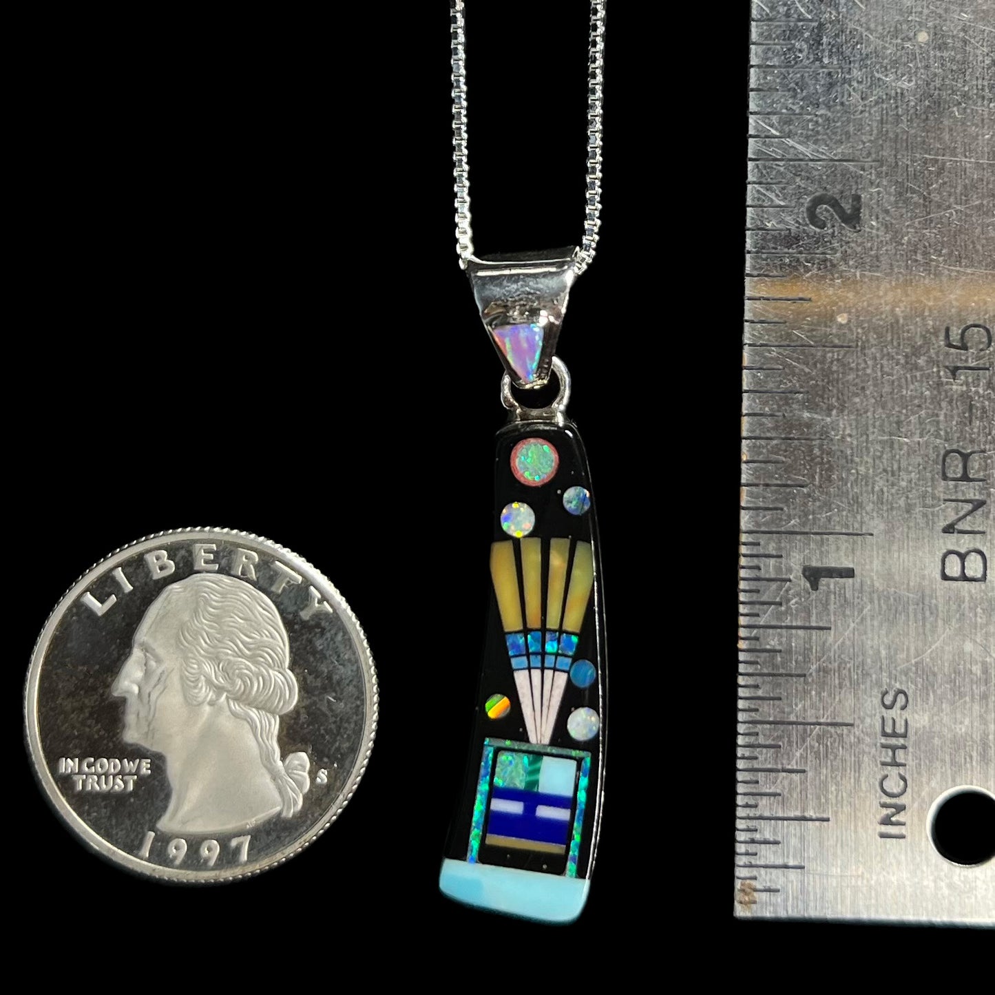1.75 inch-long men's sterling silver opal and onyx inlay necklace on black background next to ruler and US quarter coin.