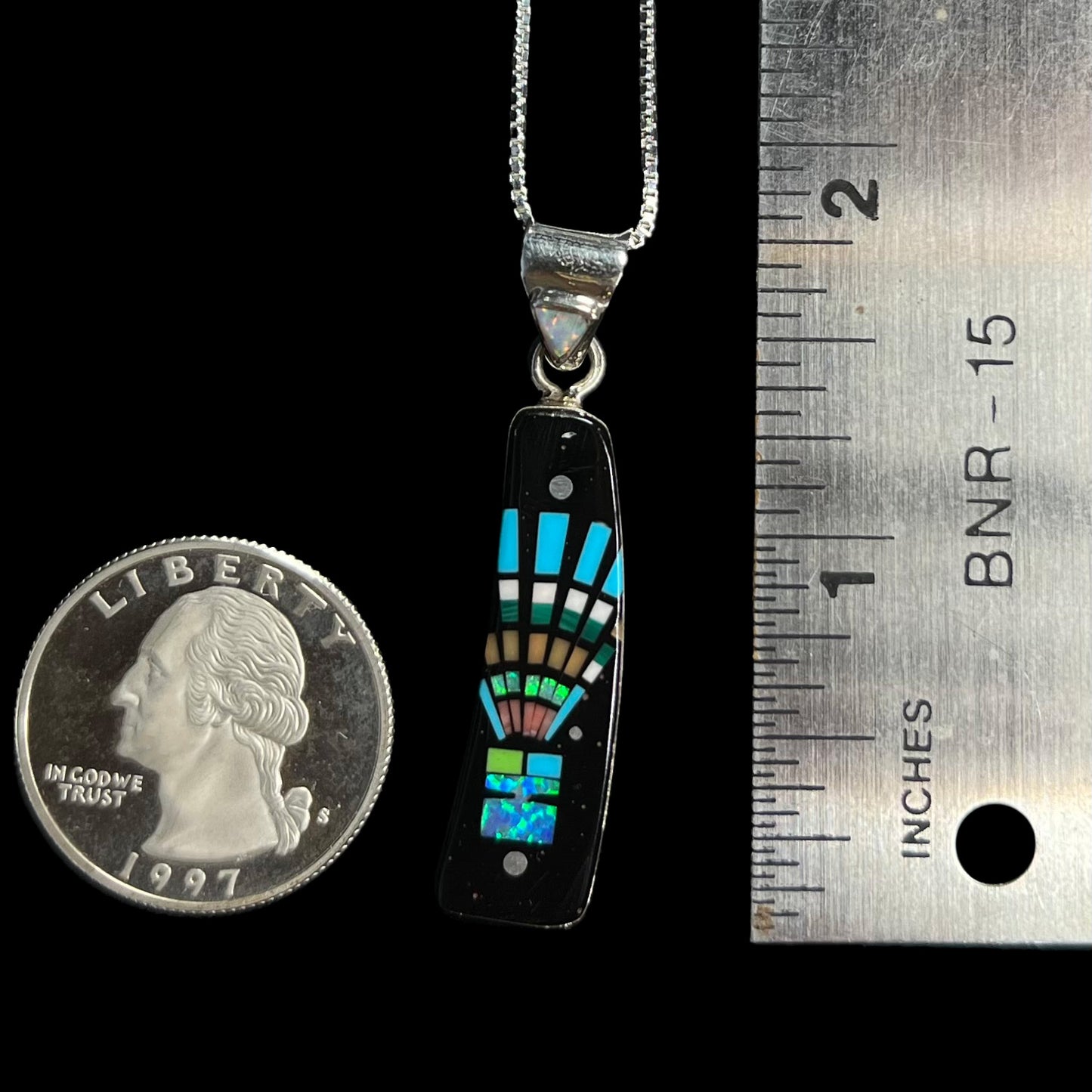 1.8 inch-long lab opal and black onyx inlay pendant with kachina headdress motif next to ruler and US quarter coin.