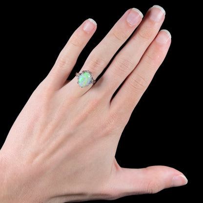 A green 1.89ct opal mounted in a platinum and diamond-accented setting on a hand.