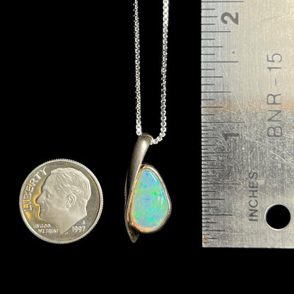 A 1 inch-long green Australian crystal opal pendant in sterling silver, shown next to a dime coin and a ruler.