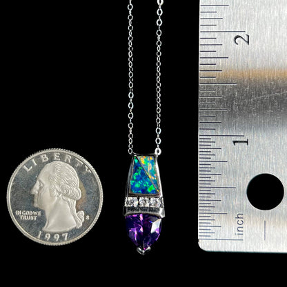 A 1 inch-long sterling silver opal inlay and purple CZ drop pendant on a silver cable chain between a US quarter coin and ruler for scale.