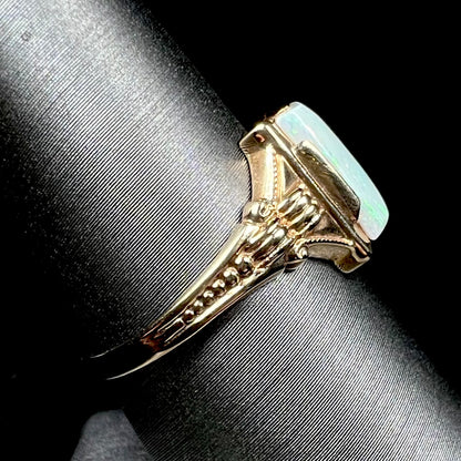 Side shank view of a 10k gold Art Deco opal solitaire ring on a ring display